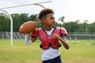 Young boy wearing LEGION M-80 Youth University Football Shoulder Pads and holding a football
