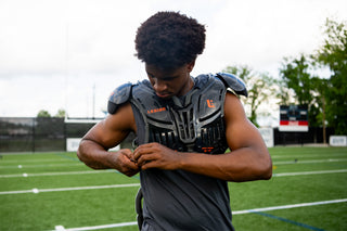 Football player adjusting LEGION M-250 Varsity Football Shoulder Pads on a field