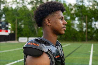 Young man wearing LEGION M-250 Varsity Football Shoulder Pads on a football field