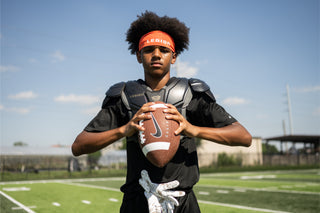 Young male athlete wearing LEGION M-150 Football Shoulder Pads and holding a football