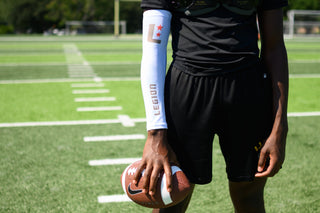 LEGION Arm Sleeve on a player holding a football on a field