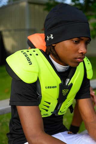 Youth wearing LEGION M-80 Highlight Football Shoulder Pads in neon green and black beanie