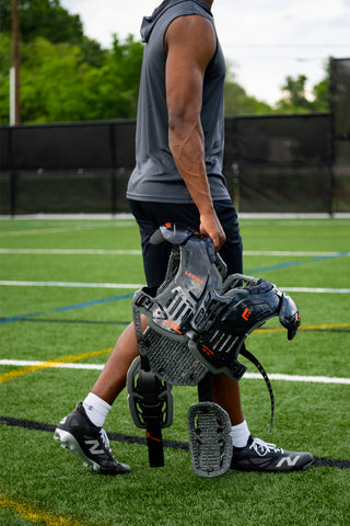 Athlete in gray sleeveless hoodie and black shorts holding Legion football shoulder pads