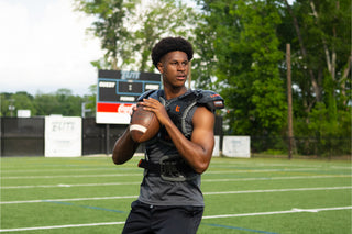 Football player wearing gray Legion shoulder pads and holding a football on a green field