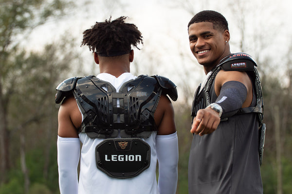 Two football players wearing Legion shoulder pads, one smiling at the camera